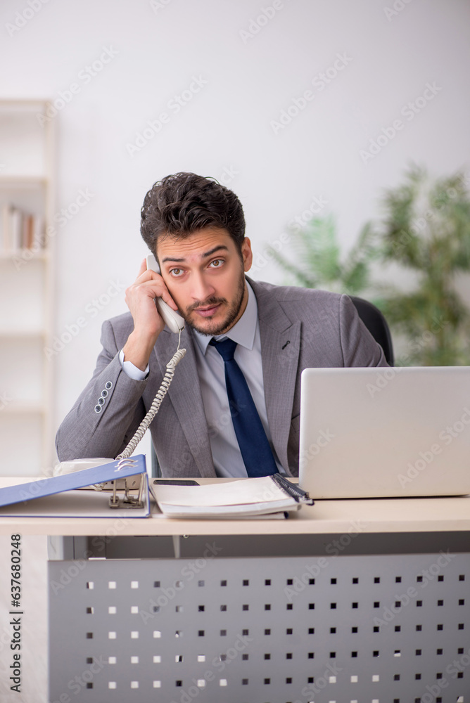 Young male employee and too much work in the office Young male employee and too much work in the office