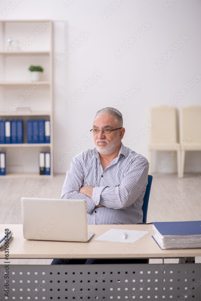 Old male employee working at workplace Old male employee working at workplace