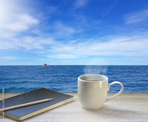 Sea, blue sky and white clouds And a fishing boat. As far as the eye can see. Coffee cups, files, glasses, diary, books, pen and notebooks for writing. Put on a brown wood table. 