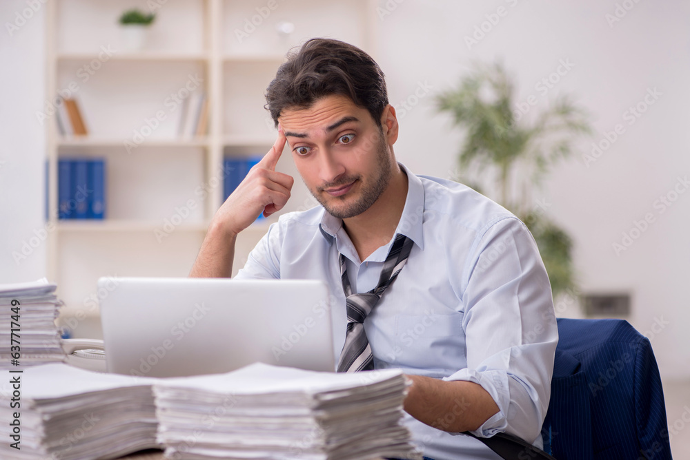 Young male employee and too much work in the office Young male employee and too much work in the office