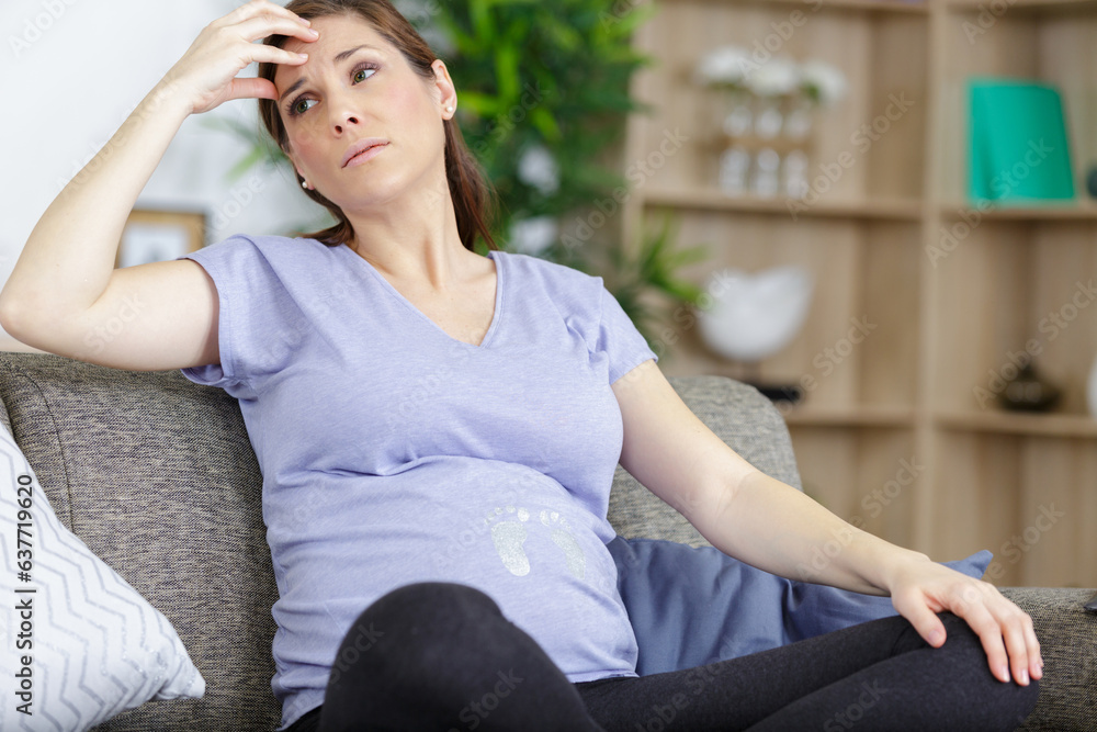 worried pregnant woman sitting on sofa worried pregnant woman sitting on sofa