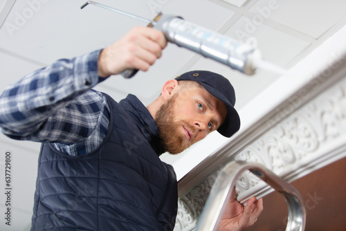 man applying silicone sealant with caulking gun photo