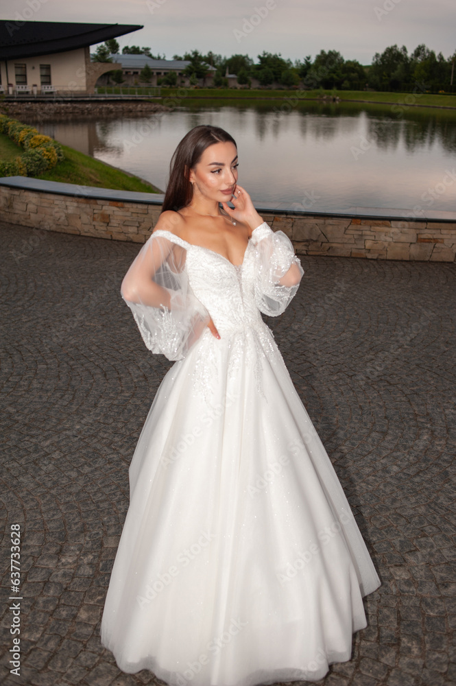 Beautiful bride in wedding dress posing on sunset near lake Beautiful bride in wedding dress posing on sunset near lake
