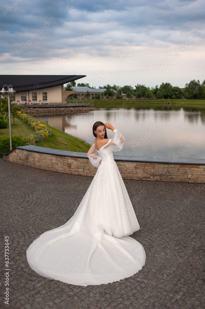 Beautiful bride in wedding dress posing on sunset near lake Beautiful bride in wedding dress posing on sunset near lake