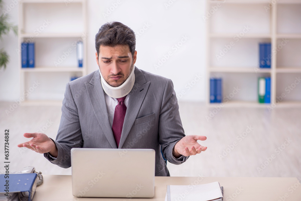 Young male employee after car accident sitting in the office