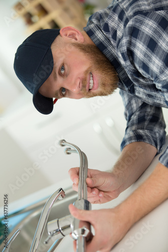 man fixing sink pipe in kitchen