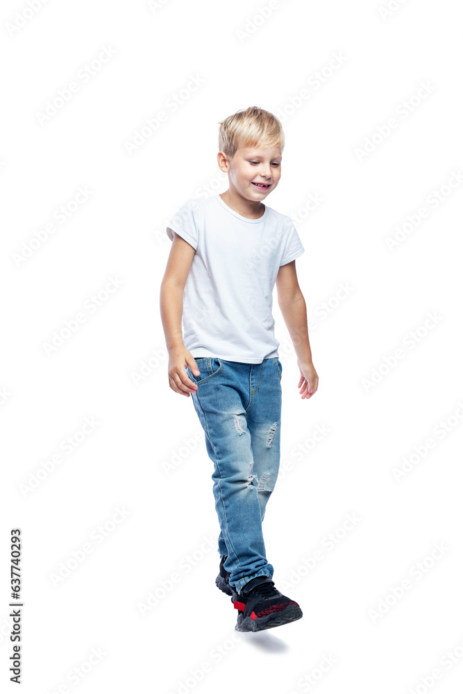 The smiling boy is walking. School age boy in a white T-shirt and jeans. movement and activity. Full height. Isolated on white background. Vertkial. The smiling boy is walking. School age boy in a white T-shirt and jeans. movement and activity. Full height. Isolated on white background. Vertkial.