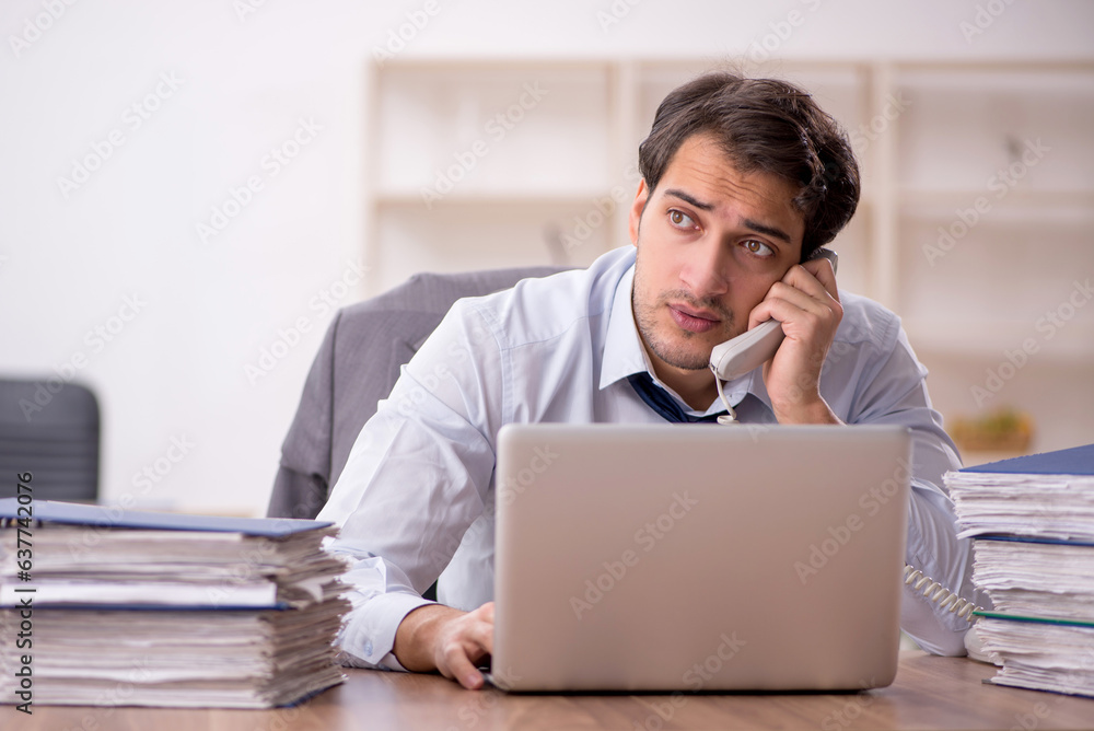 Young male employee and too much work in the office Young male employee and too much work in the office
