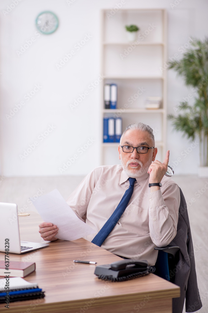 Old male employee working in the office Old male employee working in the office
