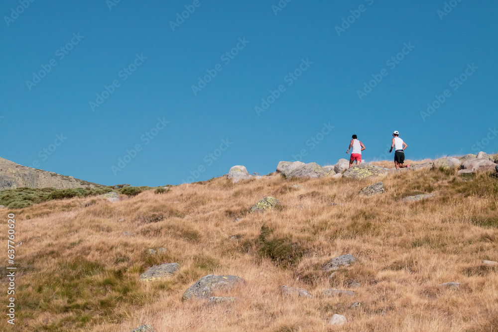 Φωτογραφία Dos corredores de montaña ascendiendo por un sendero de piedras en verano