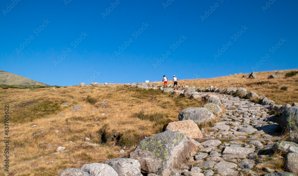 Φωτογραφία Dos corredores de montaña ascendiendo por un sendero de piedras en verano