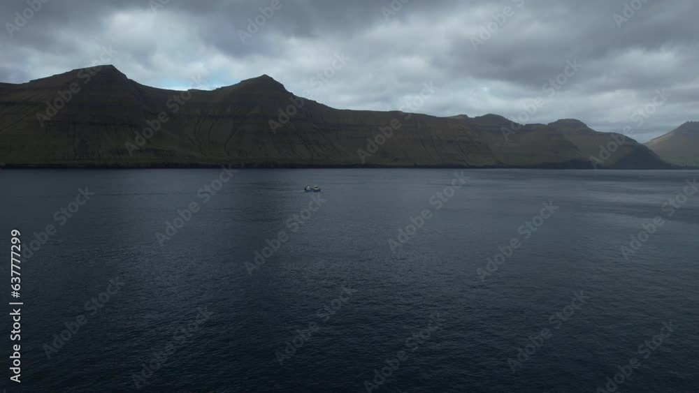 aerial view traveling in a fishing boat that sails through a fjord in the Faroe Islands and where you can see the great mountains. aerial view traveling in a fishing boat that sails through a fjord in the Faroe Islands and where you can see the great mountains.