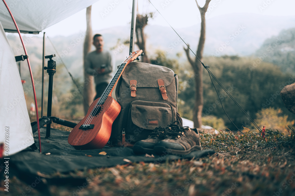 Camping equipment, bags, shoes, ukulele, tripod beside the tent in the morning. Object camp, Travel and vocation concept. Camping equipment, bags, shoes, ukulele, tripod beside the tent in the morning. Object camp, Travel and vocation concept.