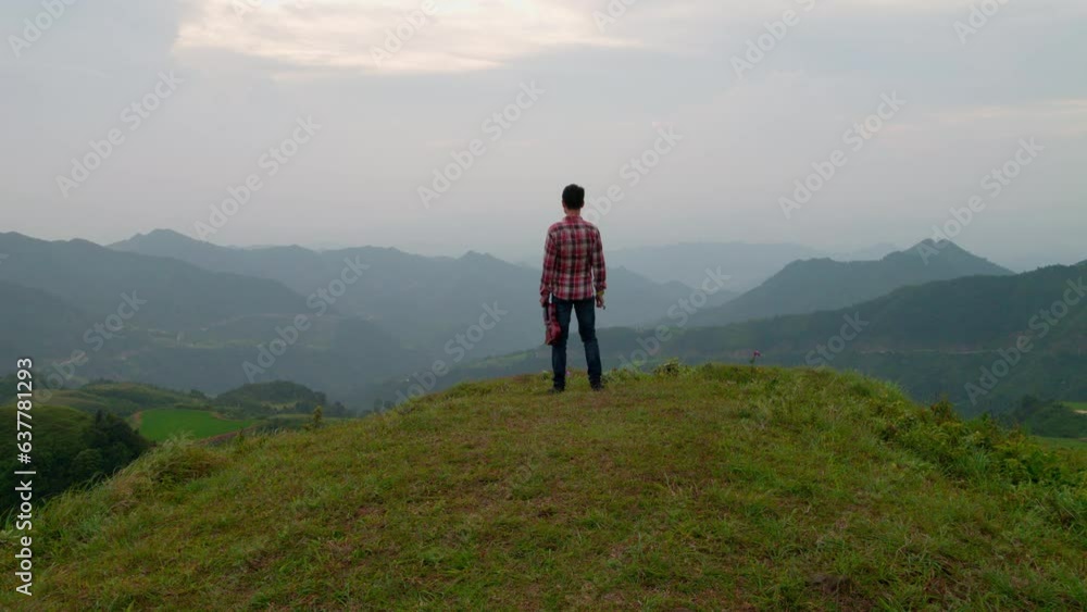 Man standing on a hill with a violin, looking out over green mountains Man standing on a hill with a violin, looking out over green mountains