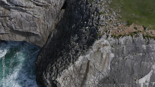 Jagged eroded limestone cliffs to grassy green hills of bufones de pria asturias spain, aerial tilt up photo