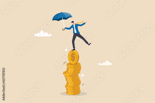 Financial stability, risk or trust, economic challenge, balance or reliability, money management, security or wealth accumulation concept, businessman hold umbrella balance on unstable coins stack. photo