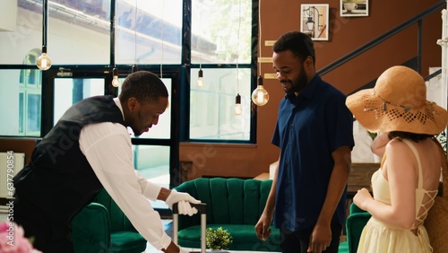 Fotografija Male tourist giving tip to bellboy helping with luggage, paying cash for luxury front desk services