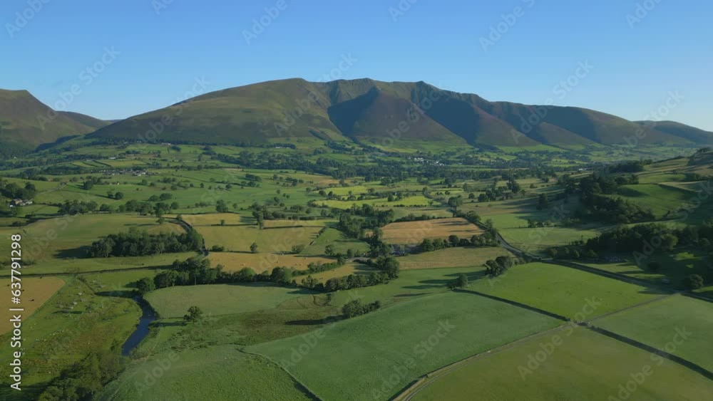 Patchwork green fields and stream with flight towards mountains on sunny summer morning in the English Lake District, Cumbria, UK. Patchwork green fields and stream with flight towards mountains on sunny summer morning in the English Lake District, Cumbria, UK.