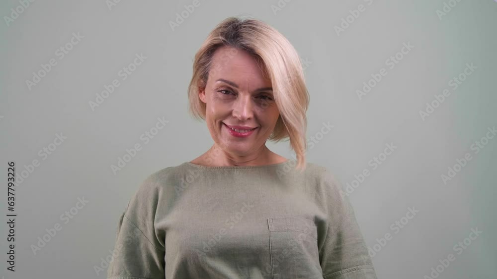 Beautiful woman looking at camera and smiling on grey background Beautiful woman looking at camera and smiling on grey background