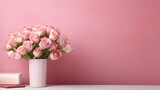 Front view of a red book mockup on an office desk with a pink wall background featuring a vase of pink flowers and copy space