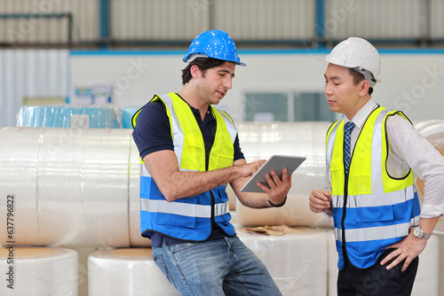 Architect or engineering man and worker sitting and checking large warehouse with computer. Multiethnic two business manager pointing and looking in future with warehouse building background.