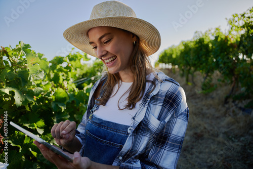 Happy young caucasian women in casual clothing pointing at digital tablet by plants on farm