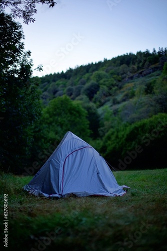 Tente légère de bivouac camping sauvage seul au milieu de la nature d'un champ et forêt le soir