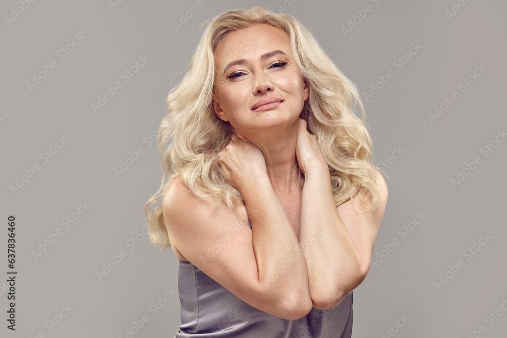 Portrait of charming beautiful adult woman with an attractive facial expression on a grey isolated background. Portrait of charming beautiful adult woman with an attractive facial expression on a grey isolated background.