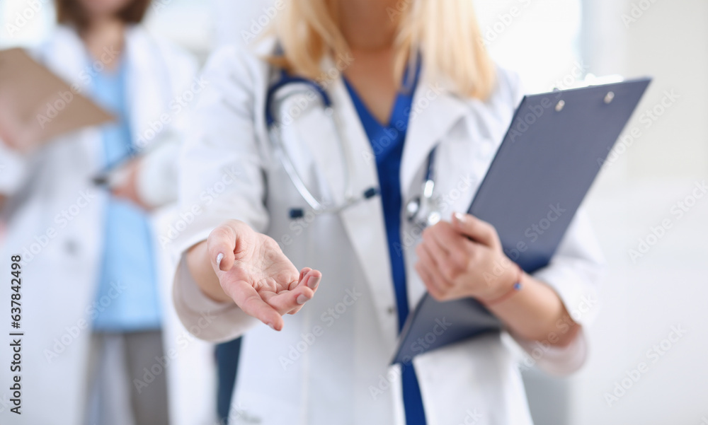 Female medicine doctor hold pad and give arm to shake in office closeup. Friend welcome introduction or thanks gesture test work examine patient congratulation help exam teamwork deal concept Female medicine doctor hold pad and give arm to shake in office closeup. Friend welcome introduction or thanks gesture test work examine patient congratulation help exam teamwork deal concept