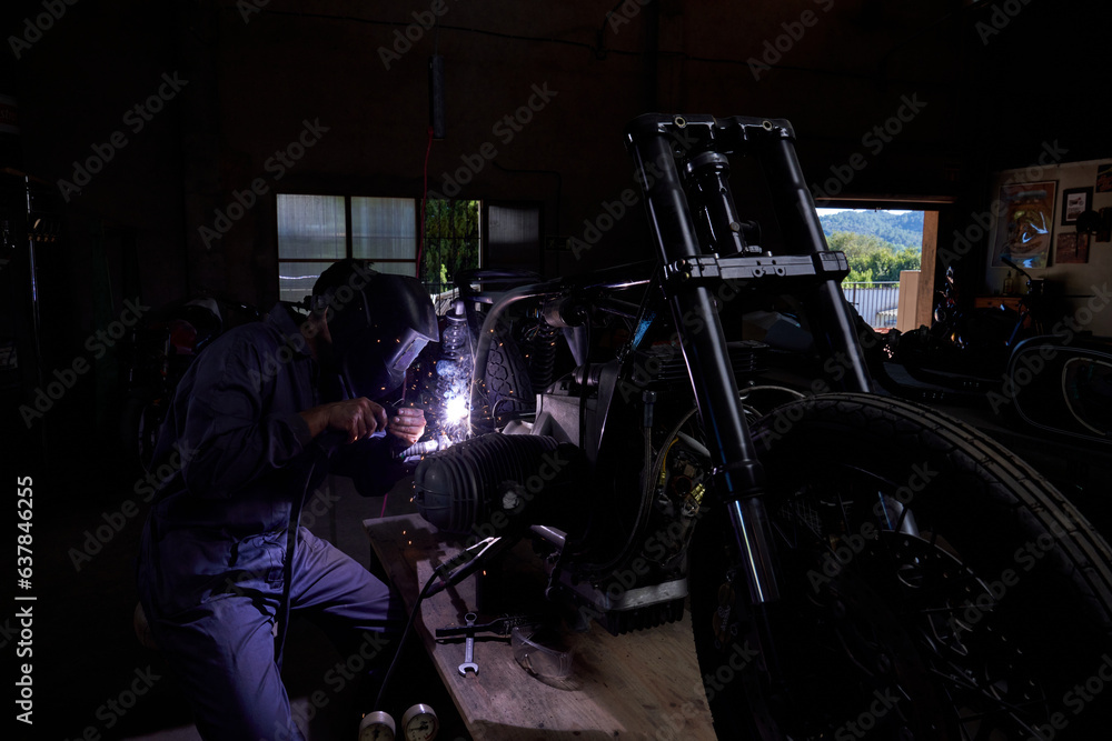 Unrecognizable mechanic repairing motorbike in garage