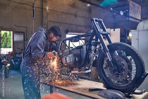 Mechanic using angle grinder while repairing motorcycle