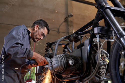 Focused mechanic repairing motorbike using angle grinder