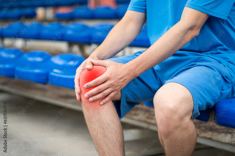 Naklejka premium Diseases of the knee joint, bone fracture and inflammation, athletic man on a sports ground after workout suffering from pain in leg and doing self-massage