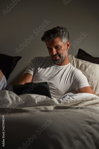Content mature man with tablet in bedroom