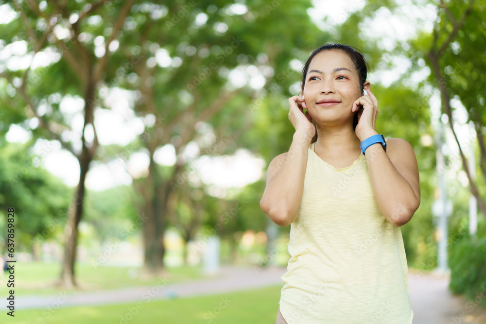 Beautiful smart and good looking Asian adult woman checking on a smartwatch or fitness tracker while practicing running - jogging at the park. Beautiful smart and good looking Asian adult woman checking on a smartwatch or fitness tracker while practicing running - jogging at the park.