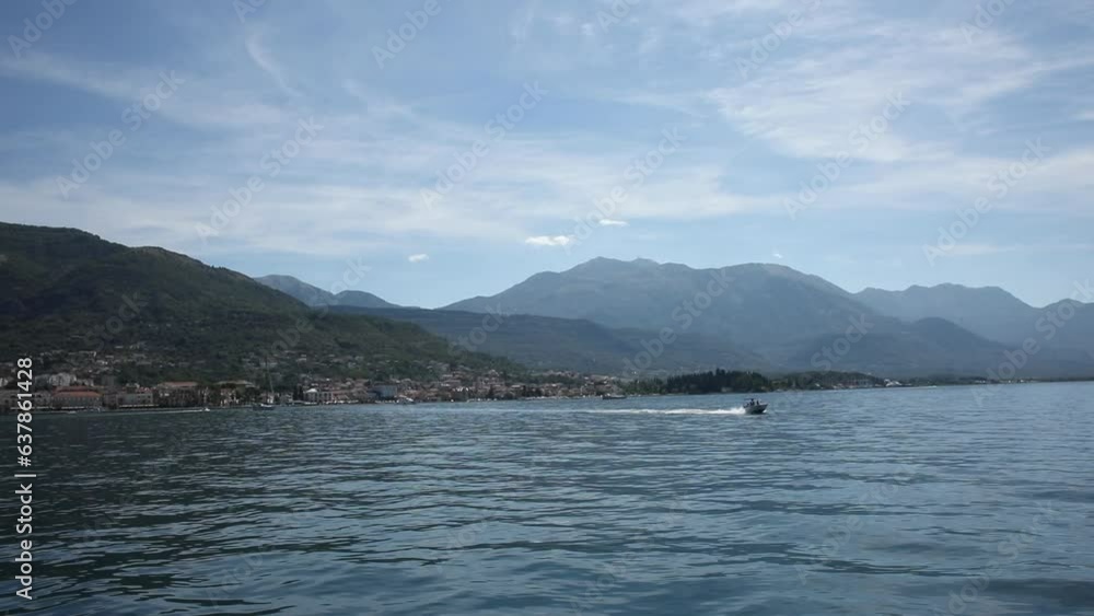 View from the deck of the yacht to the passing boat. Adriatic sea and mountains on the coast. Sunny day in Kotor bay in Montenegro. View from the deck of the yacht to the passing boat. Adriatic sea and mountains on the coast. Sunny day in Kotor bay in Montenegro.