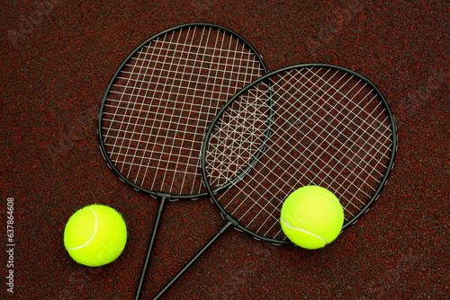 Badminton rackets and tennis balls on playground rubber coating © Atlas