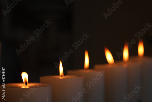 6 candles burning a flickering light in against darkened backgrond. Candle light vigil for remembering victims of crie or lost relatives.