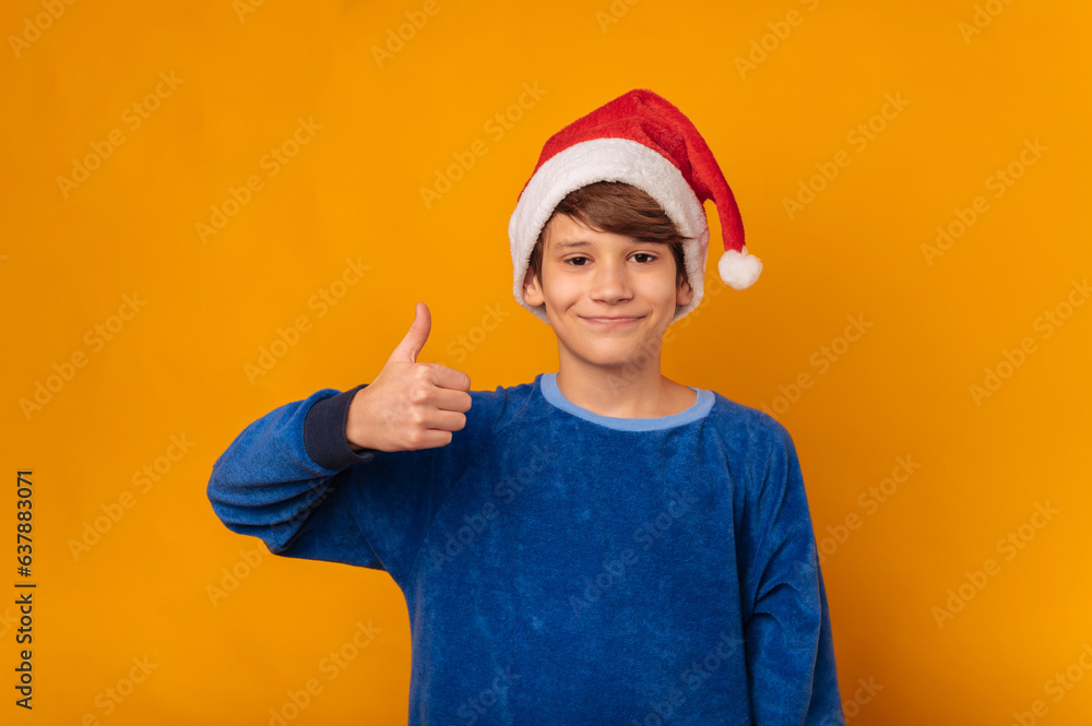 Portrait of joyful young boy showing thumb up gesture and wearing santa claus hat. Portrait of joyful young boy showing thumb up gesture and wearing santa claus hat.