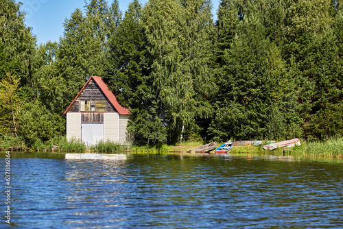 A small wooden house with boats by the riverbank © dima266f