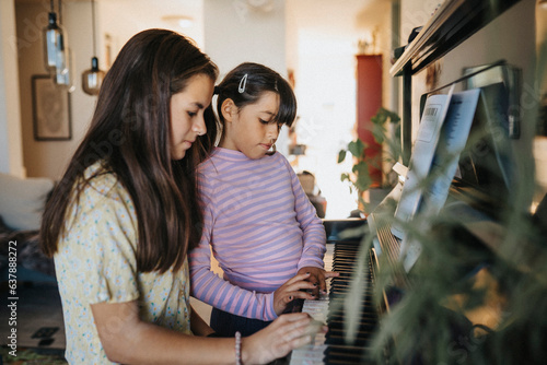 Sisters bonding over playing piano together photo