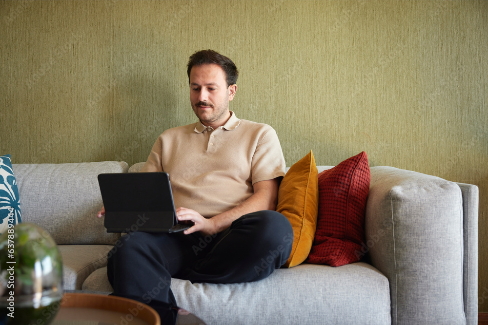 Man using laptop on sofa in living room Man using laptop on sofa in living room