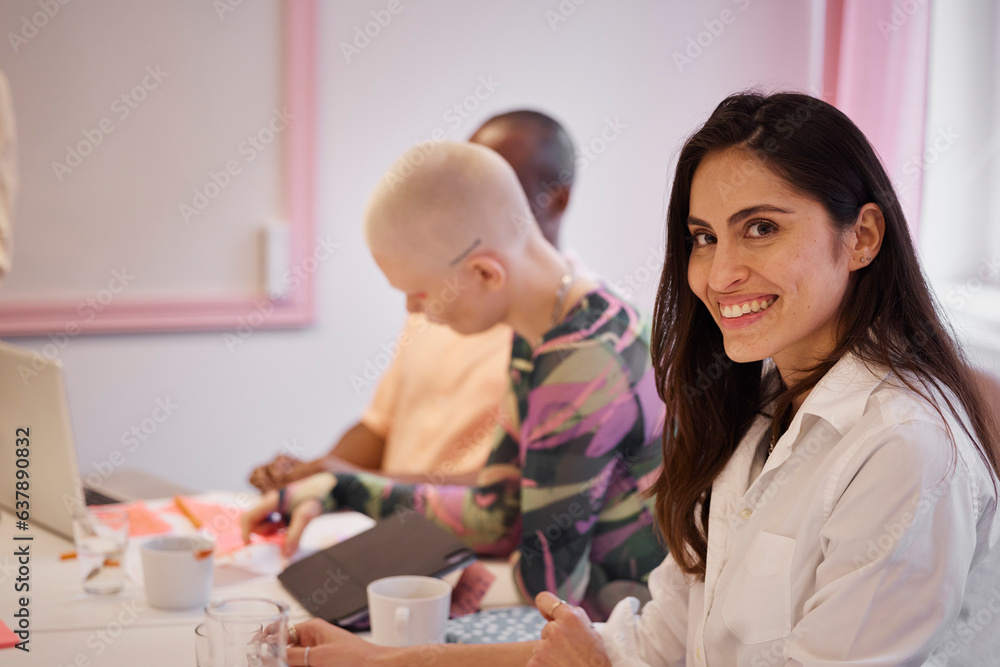 Smiling businesswoman sitting during business meeting and looking at camera Smiling businesswoman sitting during business meeting and looking at camera