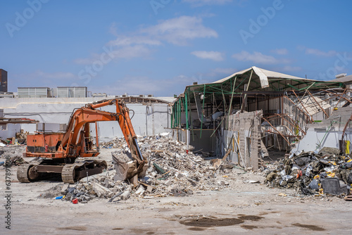 Excavator machine stopped. Industrial building in demolition process. Excavator demolishing an industrial building. Rubble.