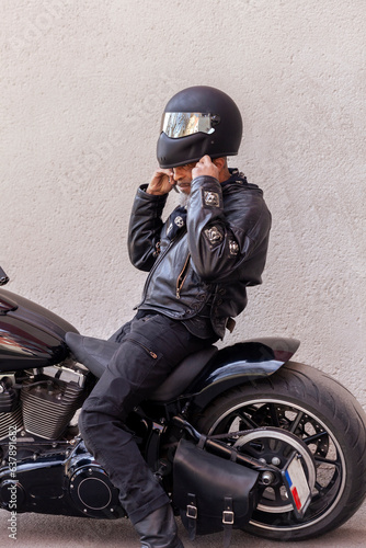 Mature biker in leather clothes putting on helmet photo