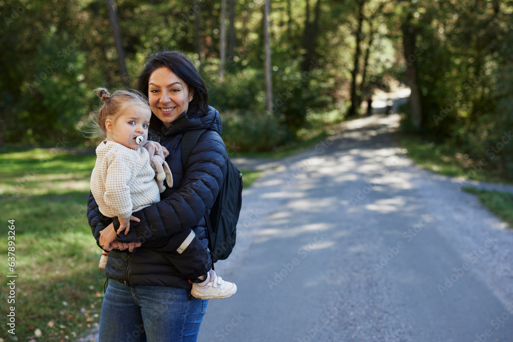 Smiling woman carry daughter and looking at camera Smiling woman carry daughter and looking at camera