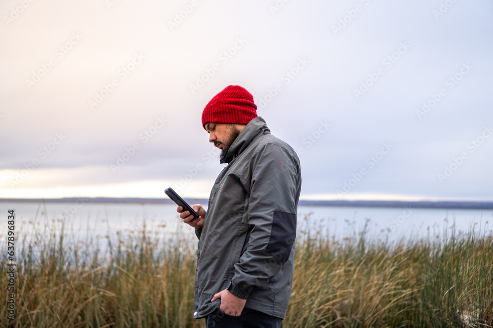 Boy with beard using mobile phone on cloudy day