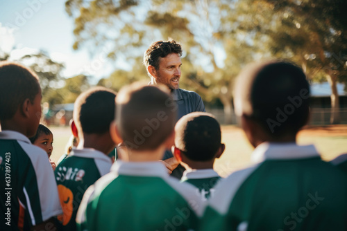 Coach having a team talk with children in a school ground