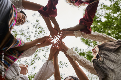 bottom view of multiethnic women in stylish clothes holding hands outdoors in retreat center
