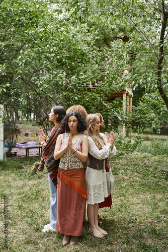 interracial women doing praying hands gesture while standing on lawn in retreat center